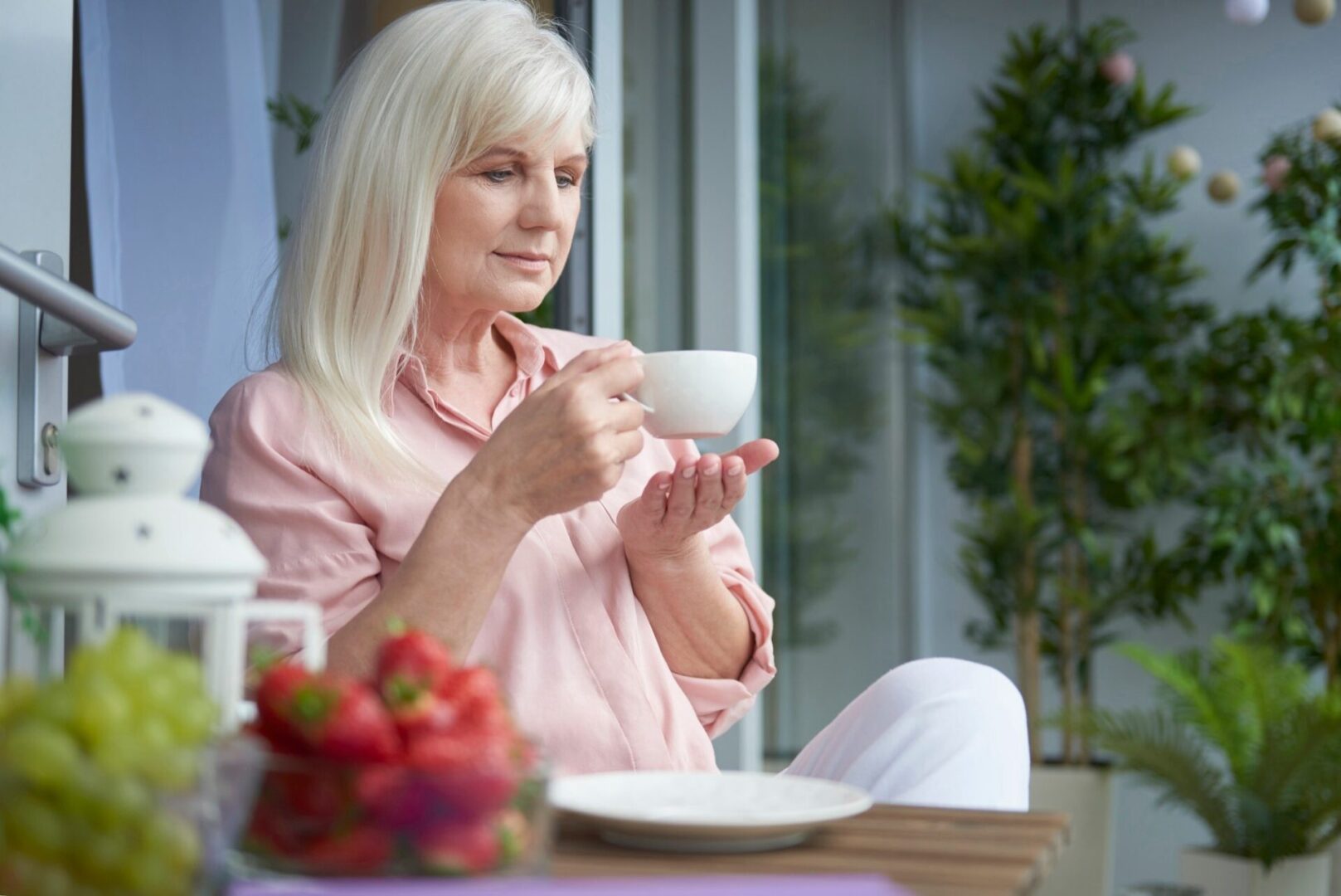 Myths and Facts About Parkinson’s and Nutrition A older lady with Parkinson's disease sitting and drinking her coffee